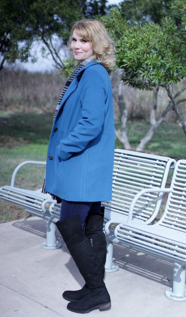 Women's winter coat in blue, paired with over the knee boots.