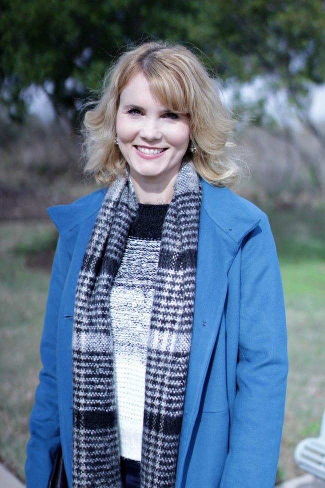 Women's winter coat in blue, paired with over the knee boots.