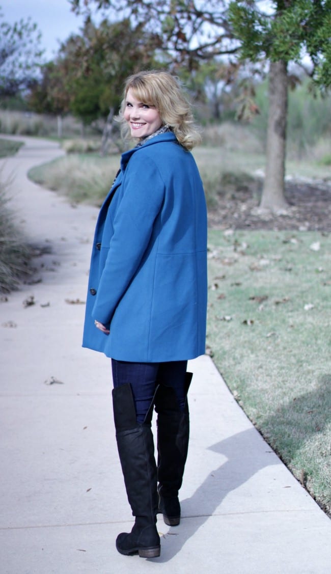 Women's winter coat in blue, paired with over the knee boots.