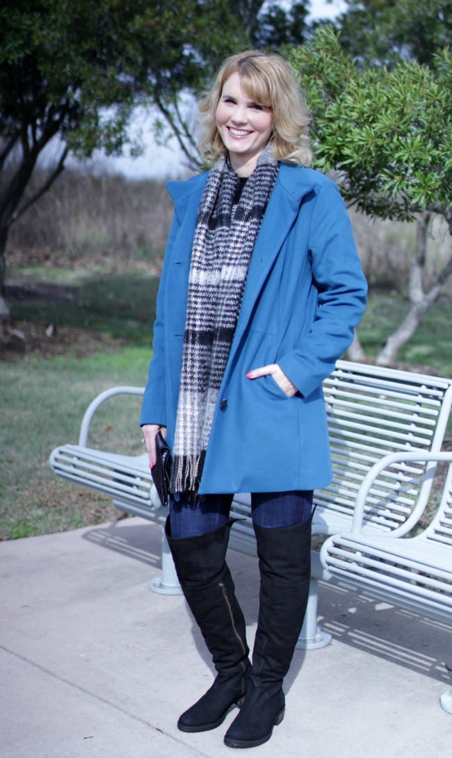 Women's winter coat in blue, paired with over the knee boots.