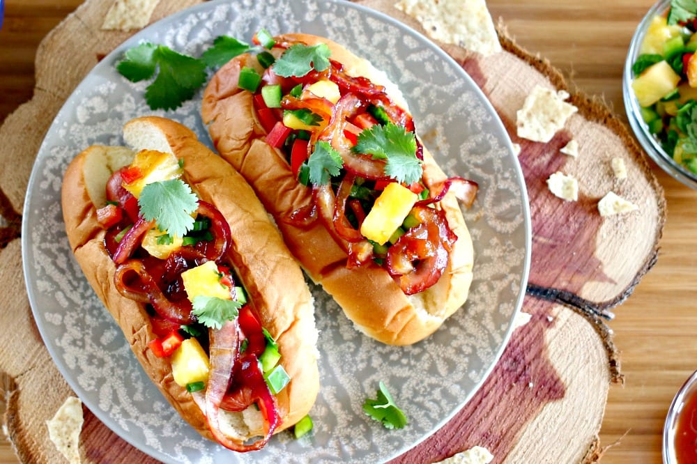 These Aloha Dogs are the perfect Game Day food. Gather up the football fans, turn on the TV and get ready for everyone to inhale these mouthwatering and super easy to prepare Hawaiian hot dogs.