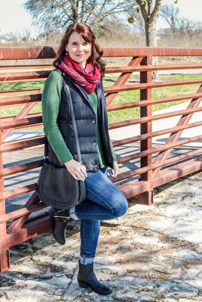 A casual Holiday outfit idea - green sweater, puffer vest, denim, red scarf and ankle boots.