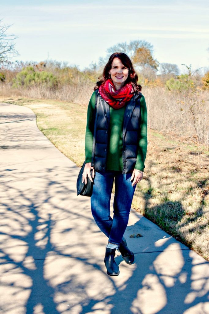 A casual Holiday outfit idea - green sweater, puffer vest, denim, red scarf and ankle boots.
