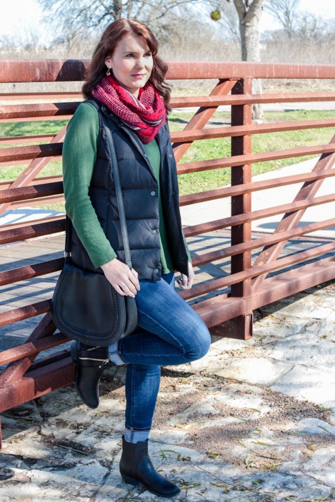 A casual Holiday outfit idea - green sweater, puffer vest, denim, red scarf and ankle boots.