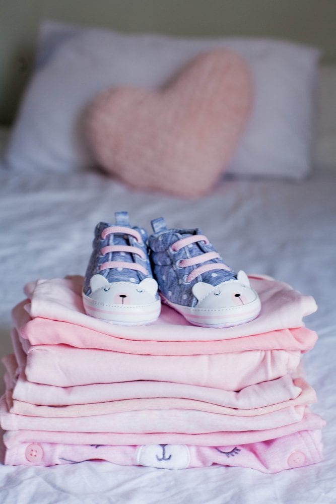 Children's Shoes And Clothes On The Bed. Beautiful Pink Baby Clo