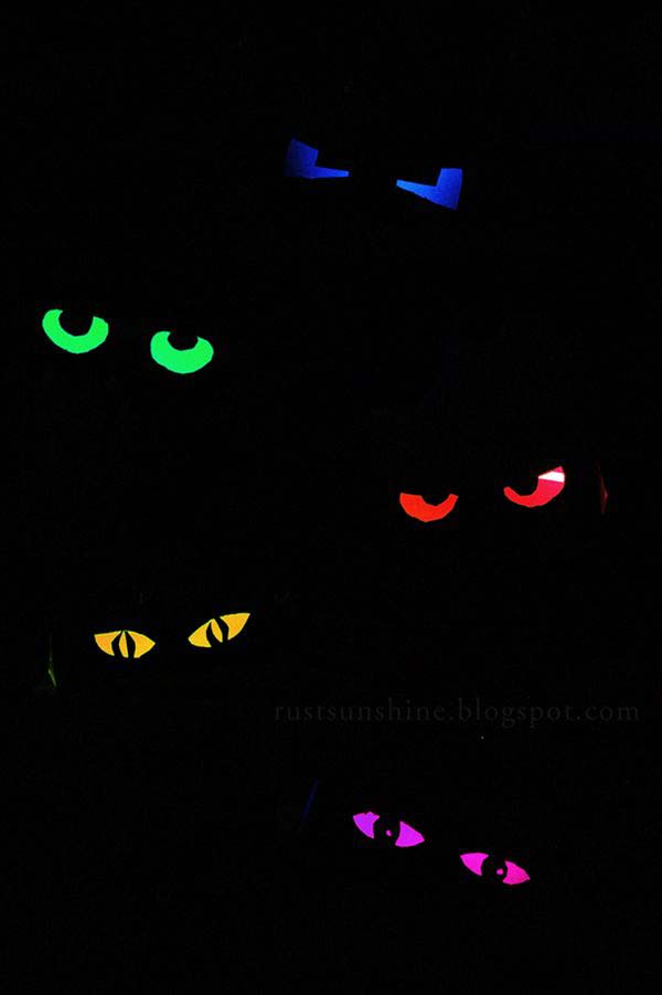 Glow-in-the-dark Multi colored eyeballs, made by placing a glow stick inside of a toilet paper tube that has eye balls cut out of it